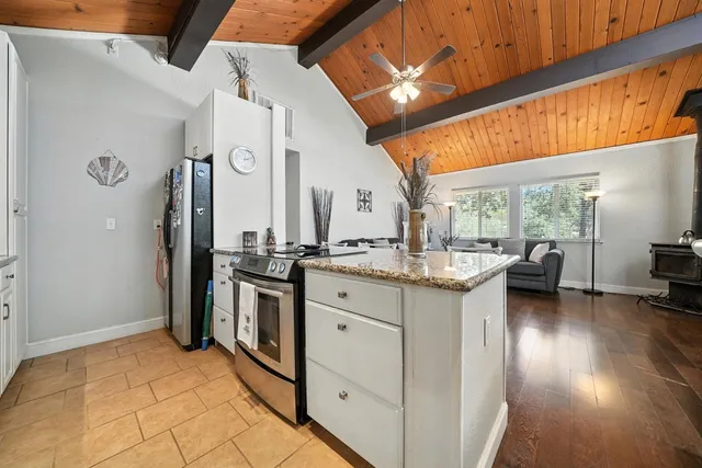 a kitchen with granite countertop a sink a stove top oven and cabinets