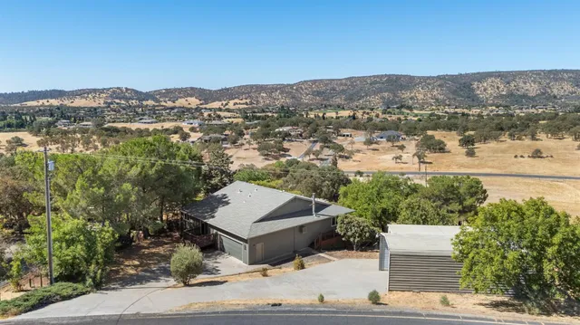 an aerial view of a house with a yard and mountain view in back