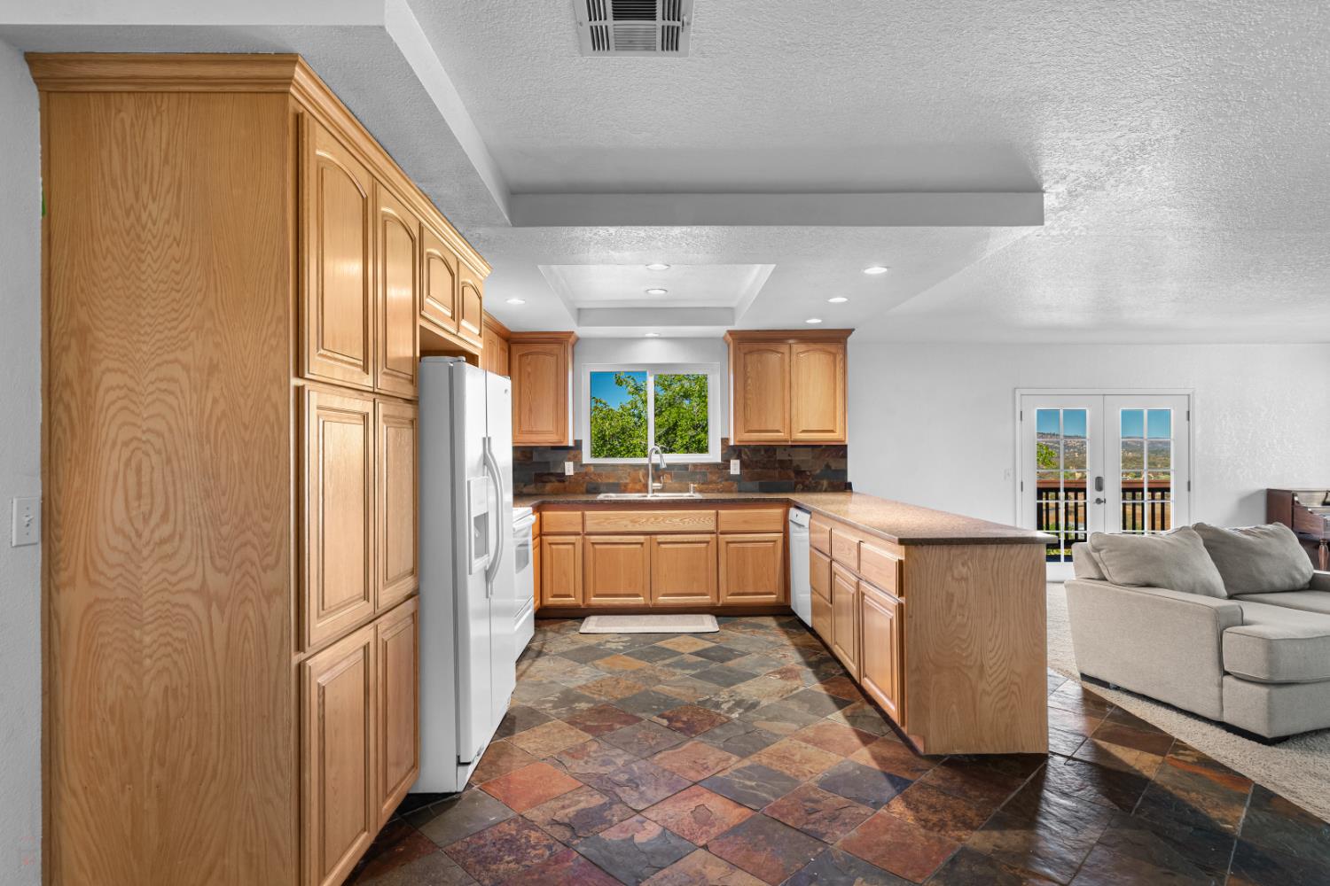 2512 Quail Hill Road Copperopolis, CA 95228 - Photo 27 of 70 a large white kitchen with granite countertop a refrigerator a sink a stove and white cabinets