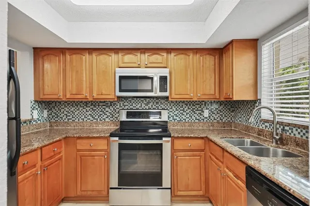 a kitchen with granite countertop stainless steel appliances a stove sink and microwave