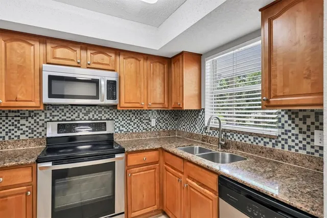 a kitchen with granite countertop a sink stove and microwave