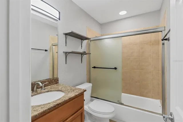 a bathroom with a granite countertop sink toilet and shower