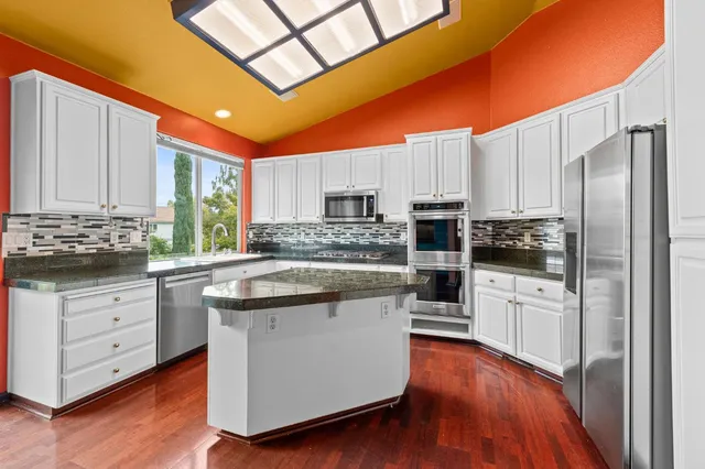 a kitchen with stainless steel appliances granite countertop a refrigerator a stove top oven a sink and dishwasher with wooden floor