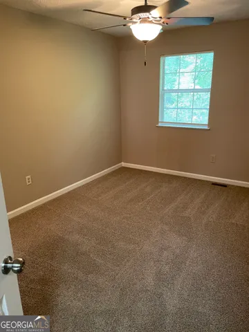 an empty room with a chandelier fan and windows