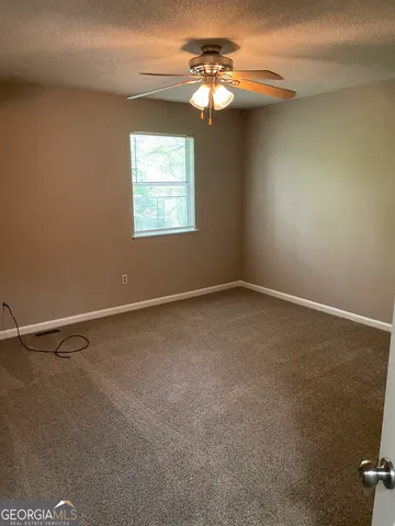 an empty room with windows and fan