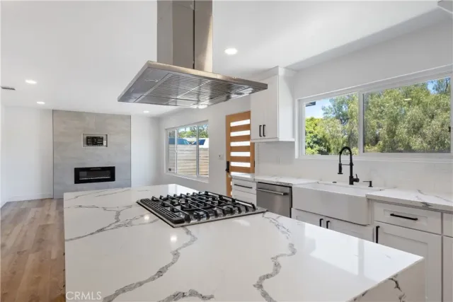 a kitchen with a sink a stove cabinets and wooden floor