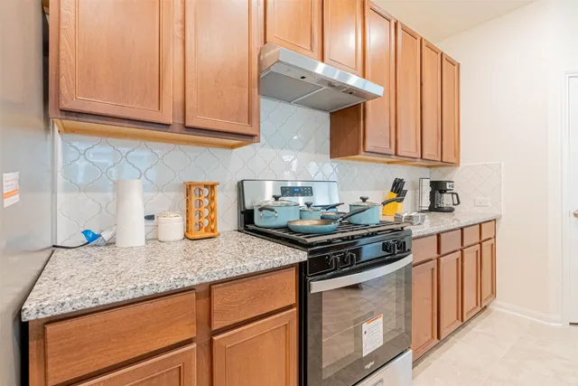 a kitchen with stainless steel appliances granite countertop a table chairs sink and cabinets