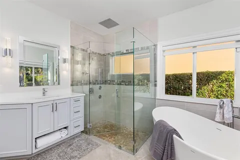 a spacious bathroom with double vanity a mirror a bathtub and a shower