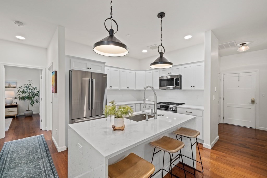 200 Revere Street, Unit 4103 Canton, MA 02021 - Photo 3 of 39 a kitchen with stainless steel appliances granite countertop a dining table chairs and white cabinets