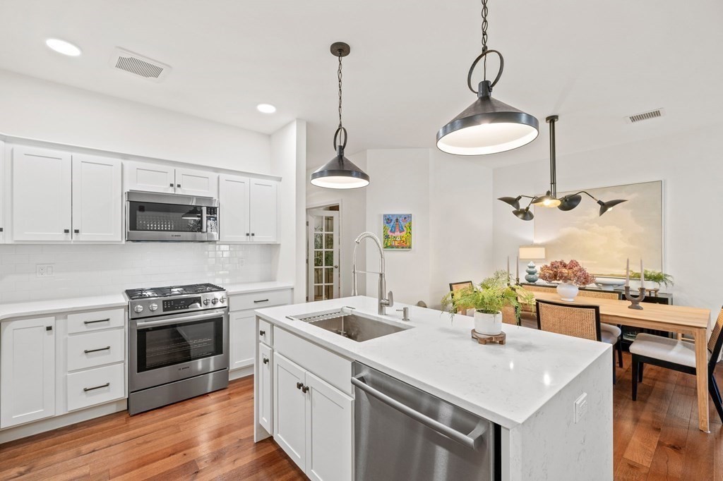 200 Revere Street, Unit 4103 Canton, MA 02021 - Photo 5 of 39 a kitchen with stainless steel appliances a stove a sink a chandelier island wooden floor and cabinets