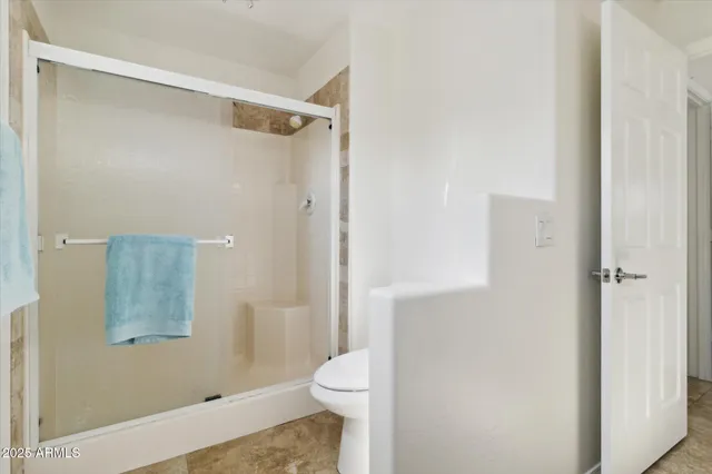 a bathroom with a granite countertop shower and a toilet