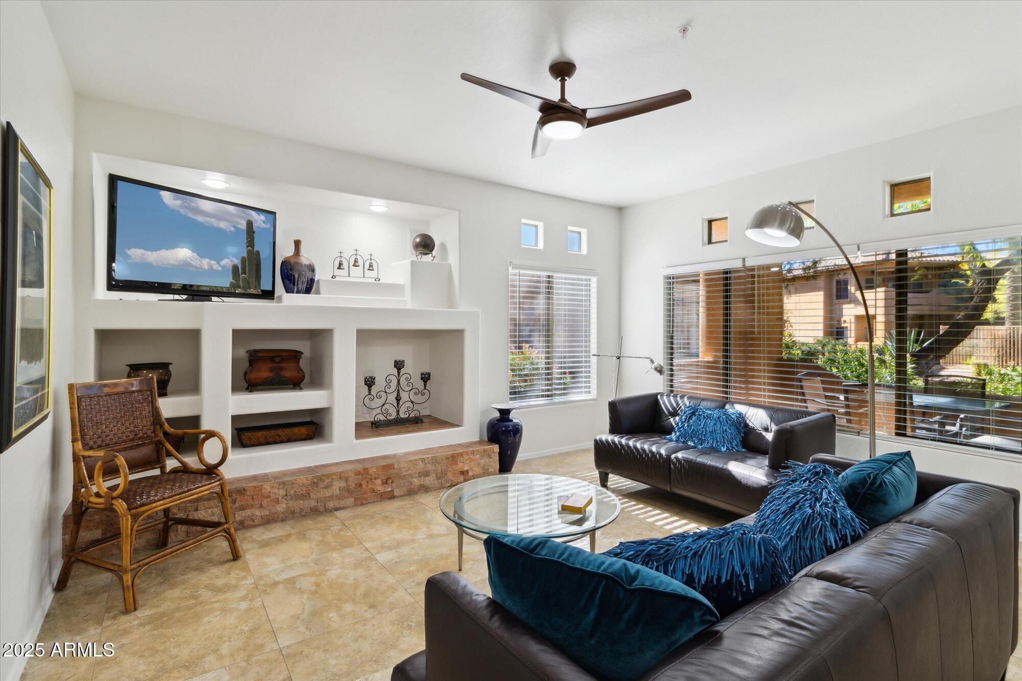 9100 East Raintree Drive, Unit 130 Scottsdale, AZ 85260 - Photo 5 of 17 a living room with furniture a fireplace and a flat screen tv