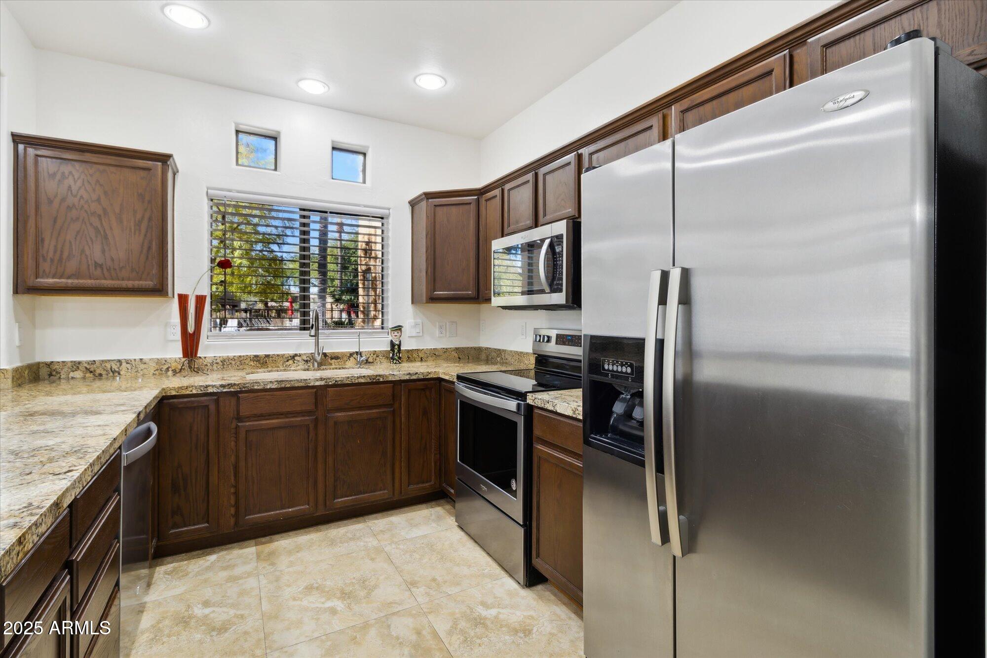 9100 East Raintree Drive, Unit 130 Scottsdale, AZ 85260 - Photo 10 of 17 a kitchen with stainless steel appliances granite countertop a refrigerator and a sink