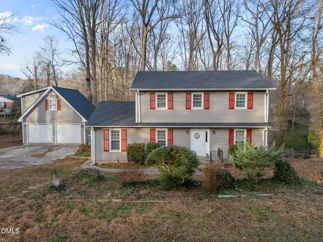 a view of a house with a yard and large trees