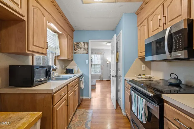 a kitchen with a sink stove and wooden floor