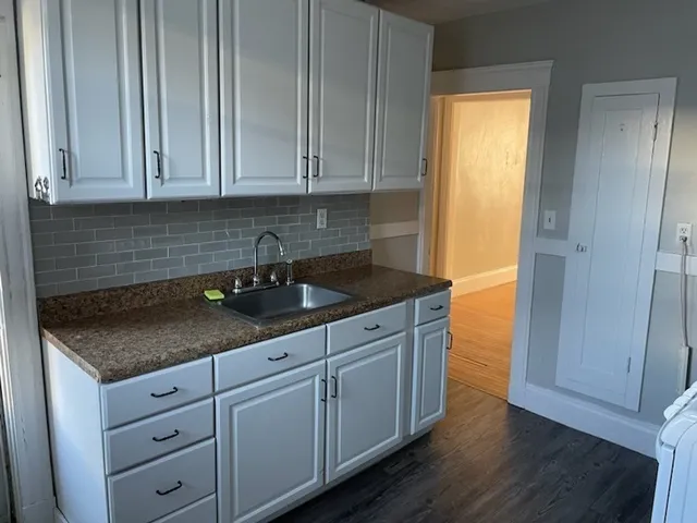 a kitchen with granite countertop white cabinets and sink