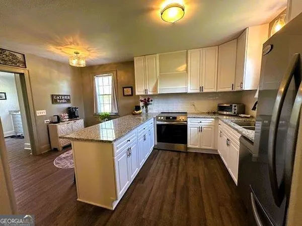 a kitchen with granite countertop a sink counter top space cabinets and stainless steel appliances