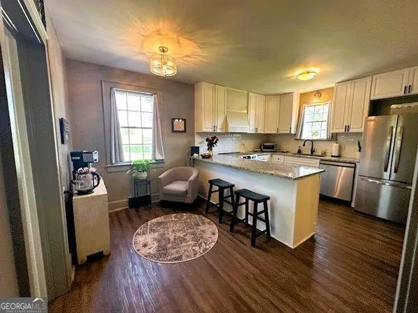 a kitchen with a refrigerator a stove a sink dishwasher and white cabinets with wooden floor