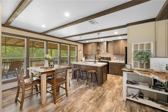 a kitchen with stainless steel appliances a dining table chairs refrigerator and sink