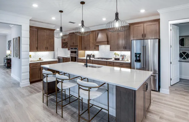 a kitchen with stainless steel appliances kitchen island granite countertop a table chairs and a refrigerator
