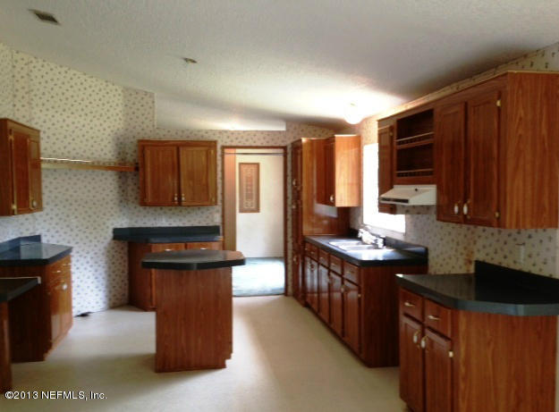 96135 Durden Road Yulee, FL 32097 - Photo 3 of 10 a kitchen with stainless steel appliances granite countertop a stove top oven a sink dishwasher and a refrigerator with wooden cabinets