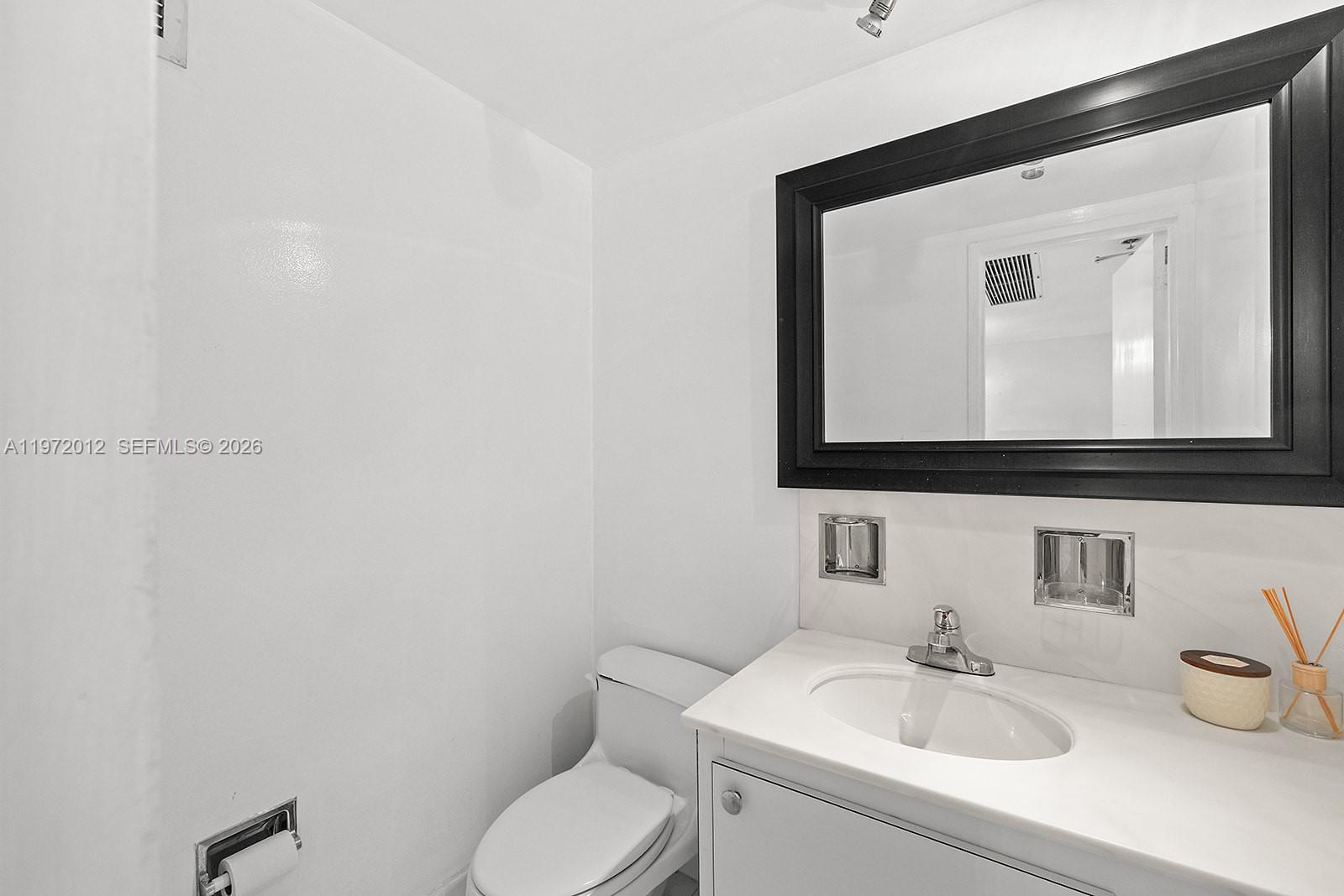 5161 Collins Avenue, Unit 910 Miami Beach, FL 33140 - Photo 13 of 18 a bathroom with a toilet sink and mirror