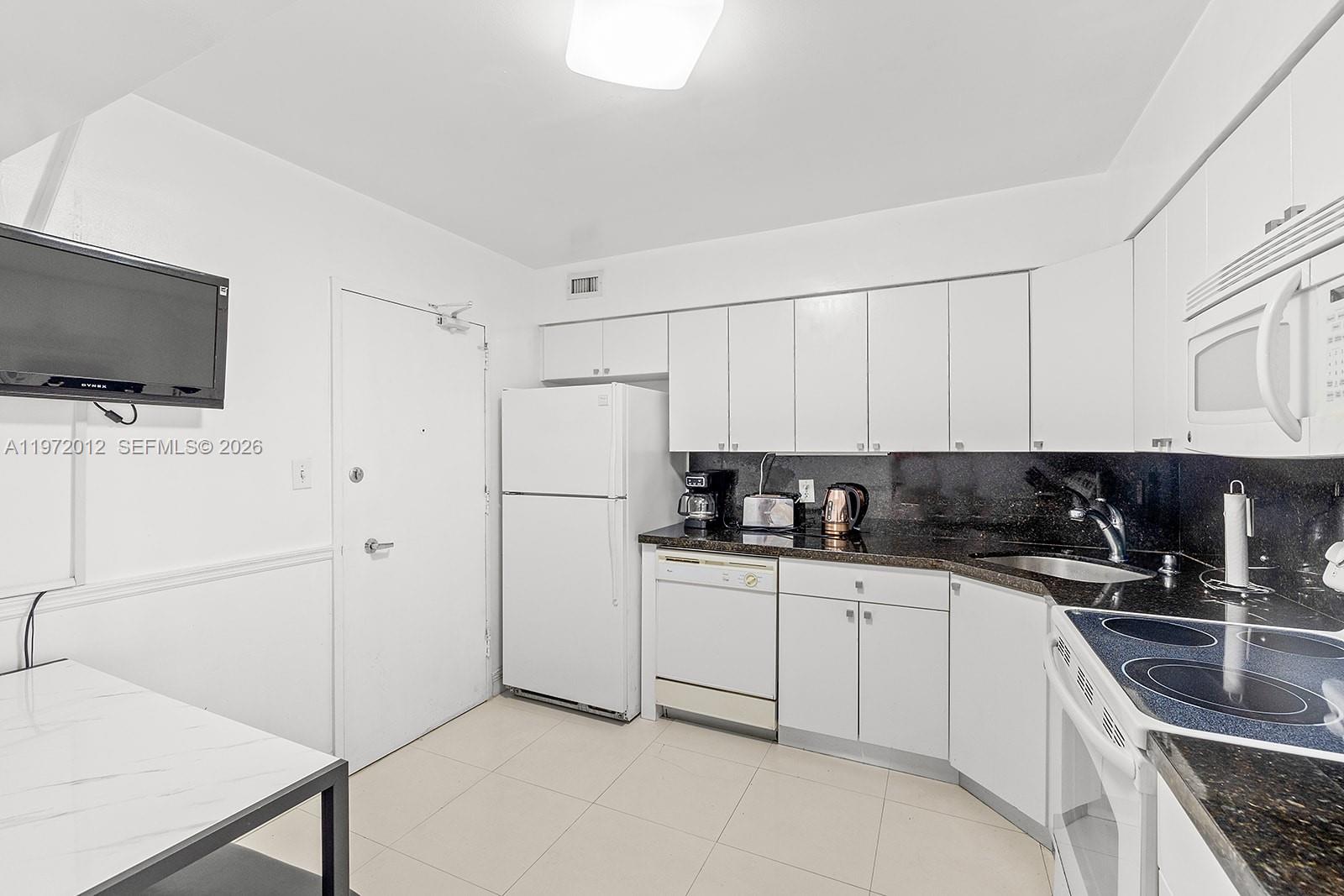 5161 Collins Avenue, Unit 910 Miami Beach, FL 33140 - Photo 6 of 18 a kitchen with stainless steel appliances a sink a stove and a refrigerator