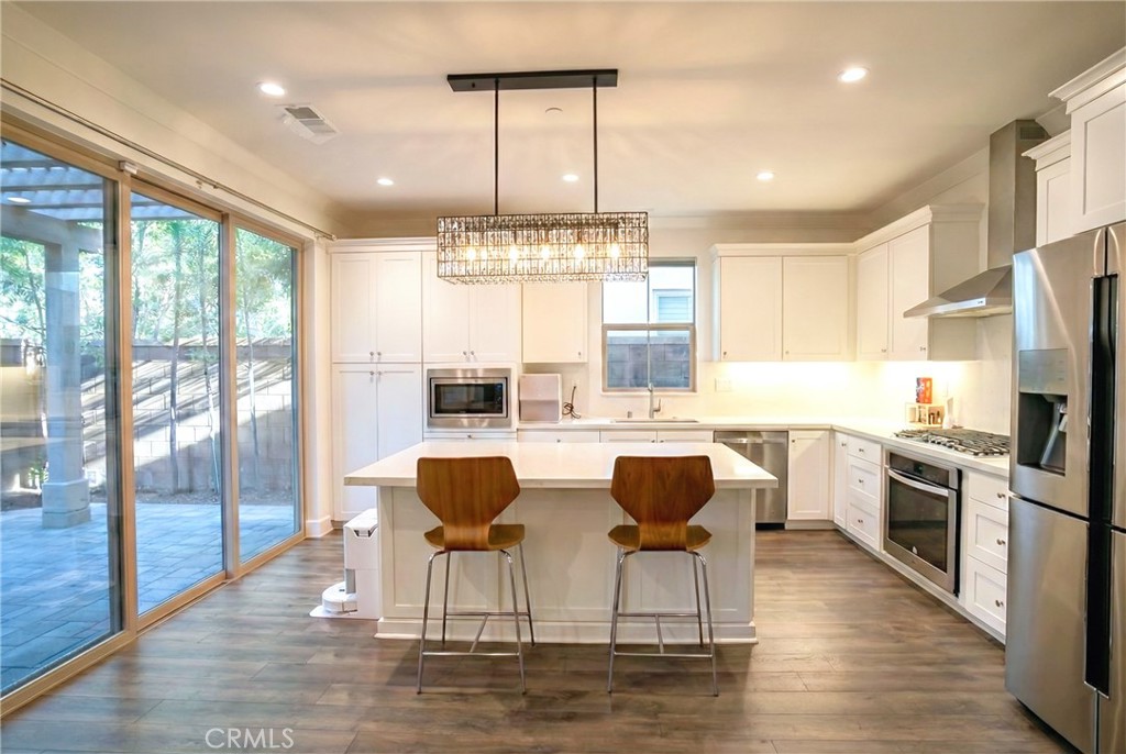 109 Sugar Cane Irvine, CA 92620 - Photo 7 of 26 a kitchen with stainless steel appliances granite countertop a stove top oven a refrigerator a dining table and chairs with wooden floor