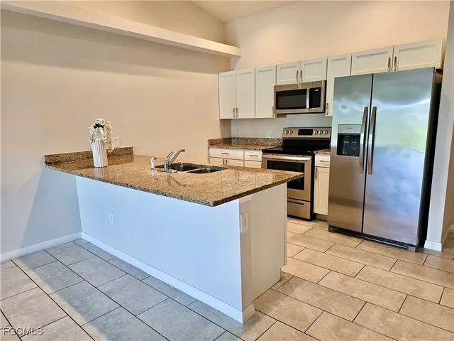 a kitchen with stainless steel appliances granite countertop a sink a stove a microwave a refrigerator a microwave and cabinets