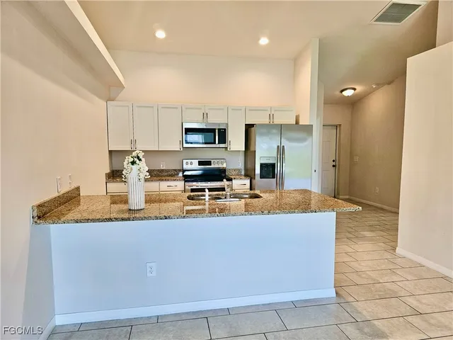 a kitchen with kitchen island granite countertop a sink a counter top space stainless steel appliances and cabinets