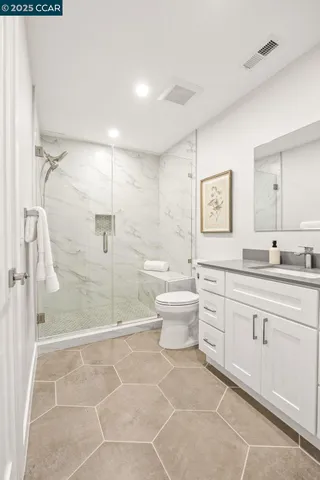 a spacious bathroom with a granite countertop sink a toilet and a shower