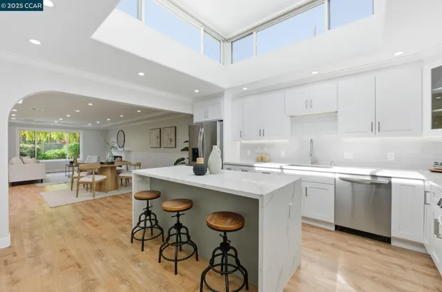 a kitchen with stainless steel appliances granite countertop a table chairs sink and cabinets