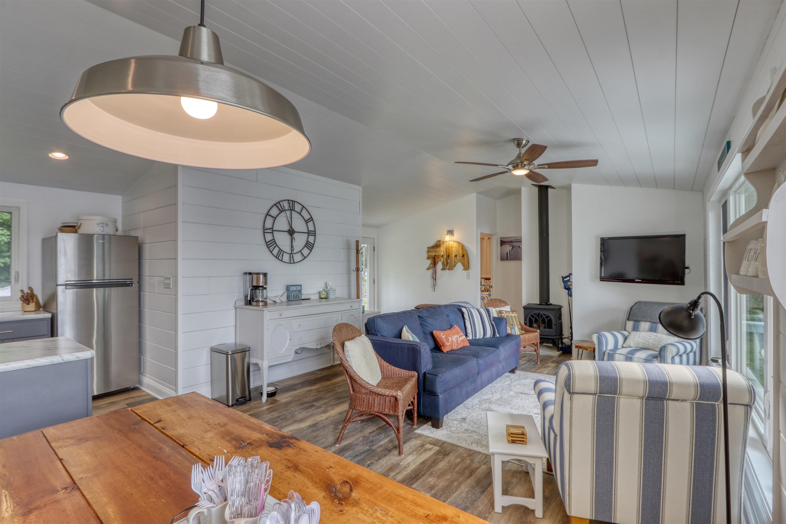 7144 Malm Road Winter, WI 54896 - Photo 29 of 58 Living room featuring a wood stove, wood finished floors, vaulted ceiling, ceiling fan, and wooden walls