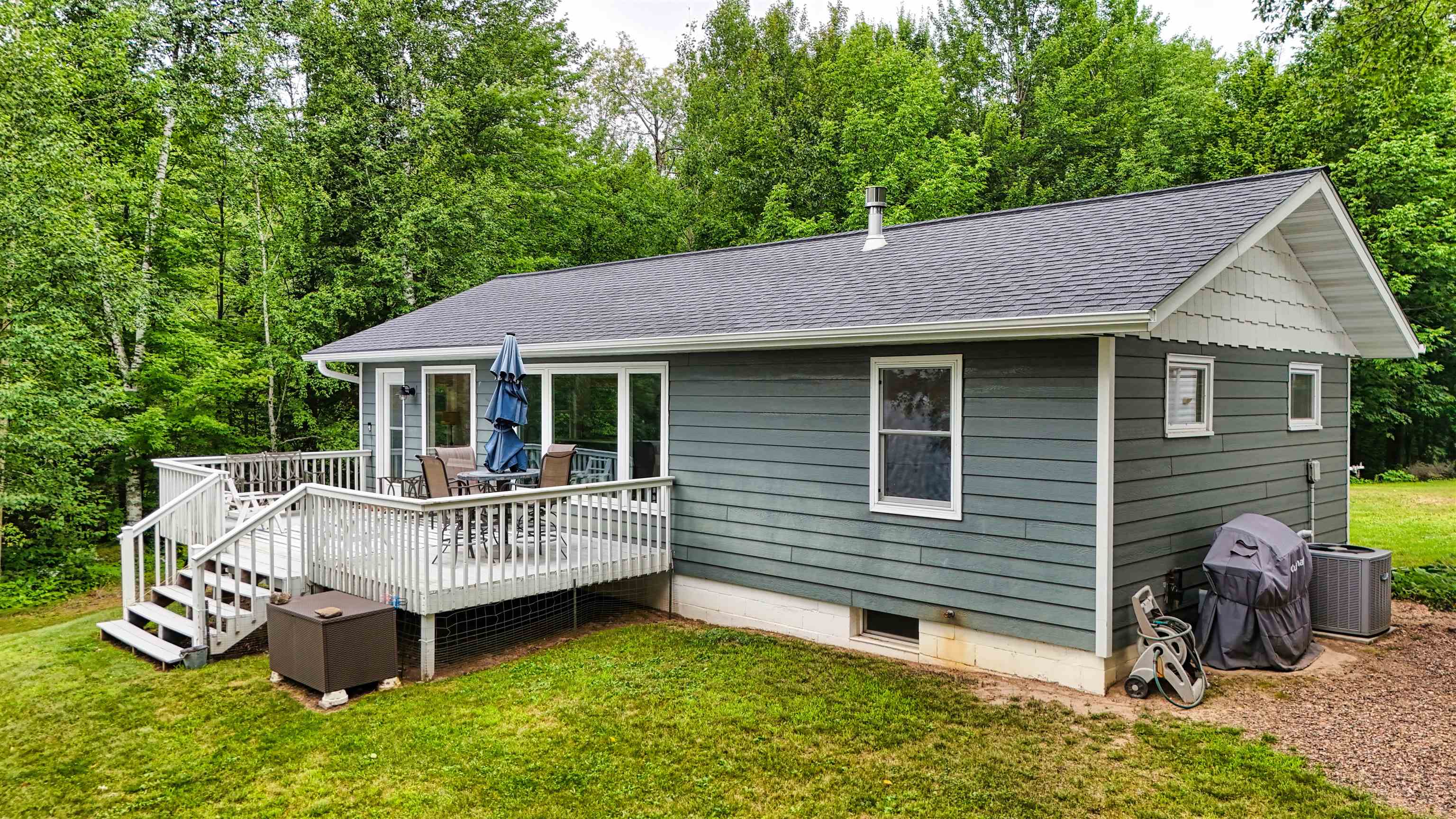 7144 Malm Road Winter, WI 54896 - Photo 5 of 58 Rear view of house featuring a shingled roof, a wooden deck, a lawn, and view of scattered trees