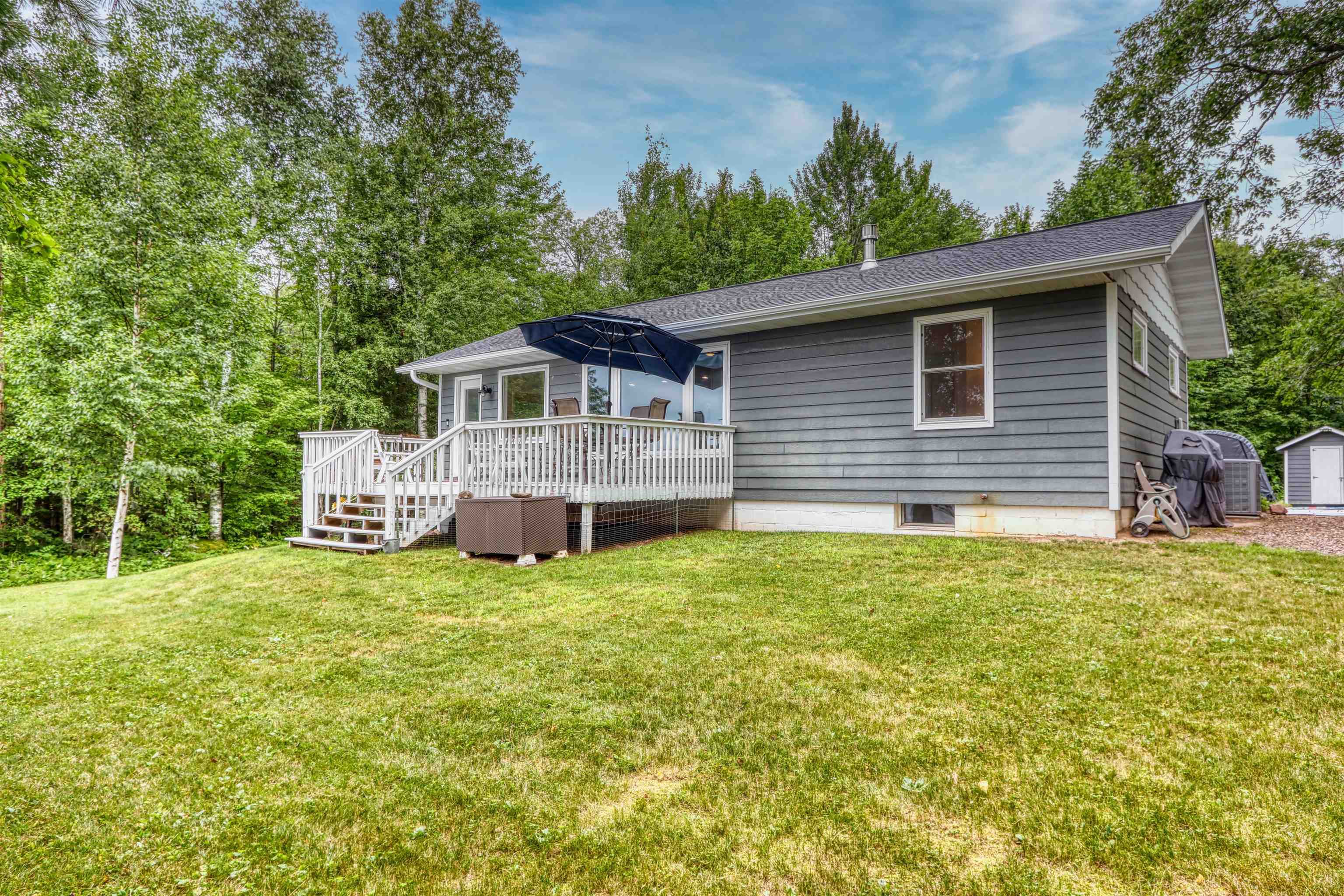 7144 Malm Road Winter, WI 54896 - Photo 53 of 58 Back of property with a wooden deck, a shed, a yard, and view of wooded area
