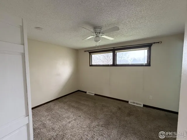 an empty room with windows and ceiling fan