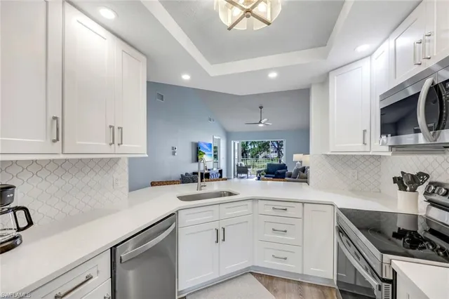 a kitchen with white cabinets white stainless steel appliances and sink