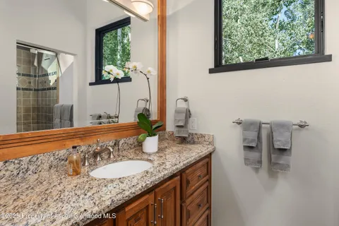 a bathroom with a granite countertop sink and a window