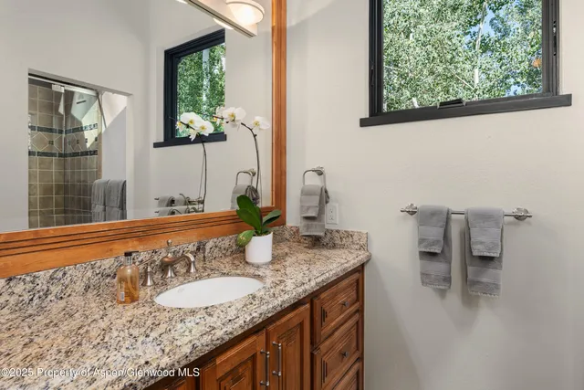 a bathroom with a granite countertop sink and a window