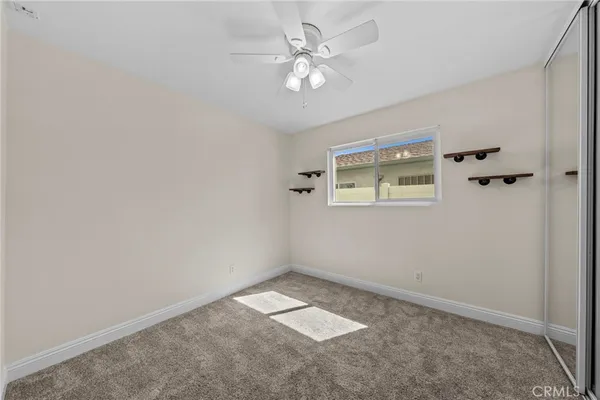 an empty room with a chandelier fan and windows