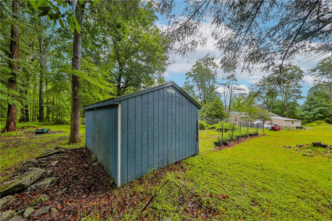 5599 Minks Pond Road Bushkill, PA 18324 - Photo 55 of 64 A quaint storage shed nestled amidst verdant trees and open green space, providing ample outdoor utility.