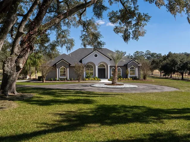 a view of house with garden and tall trees