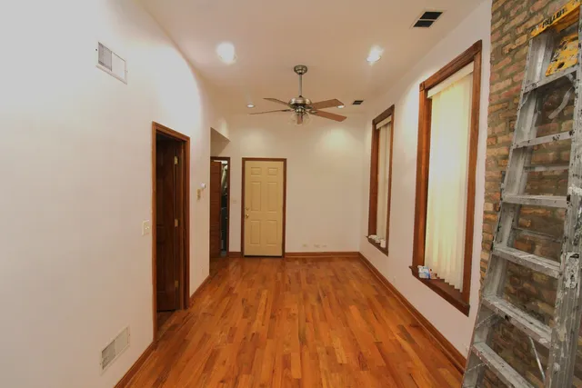 a view of a hallway with a wooden floor and a ceiling fan