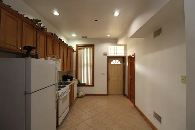 a view of a refrigerator in kitchen and an empty room