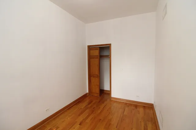 a view of an empty room with wooden floor and closet