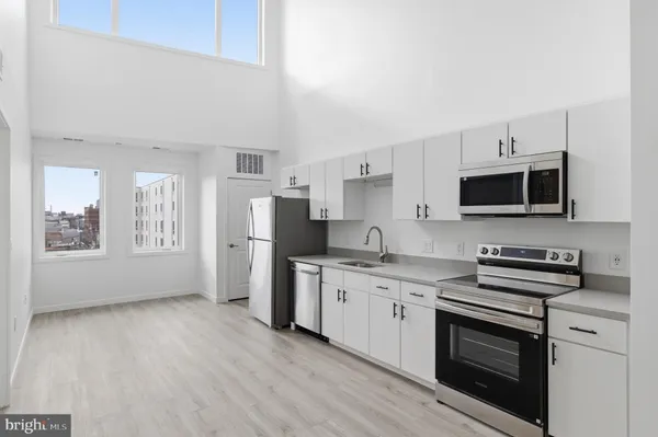 a kitchen with stainless steel appliances a stove a sink a microwave a refrigerator and cabinets