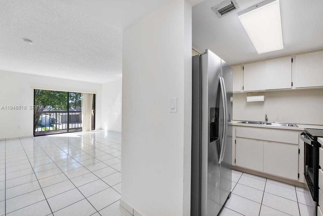 995 Southwest 84th Avenue, Unit 223 Miami, FL 33144 - Photo 6 of 25 a kitchen with white cabinets a refrigerator and a stove