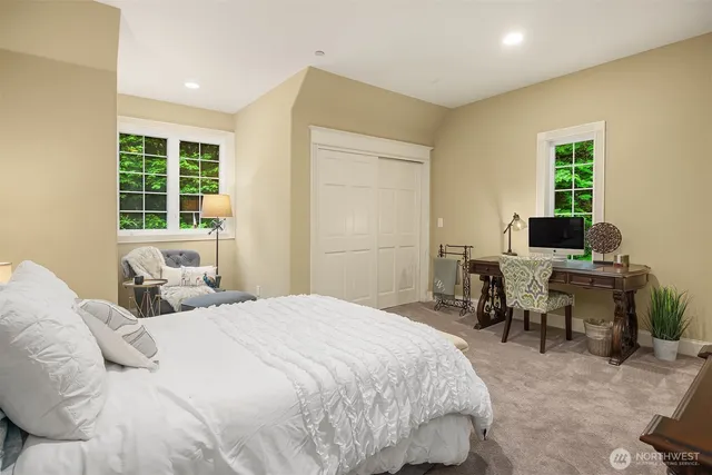 a bedroom with a bed and large windows