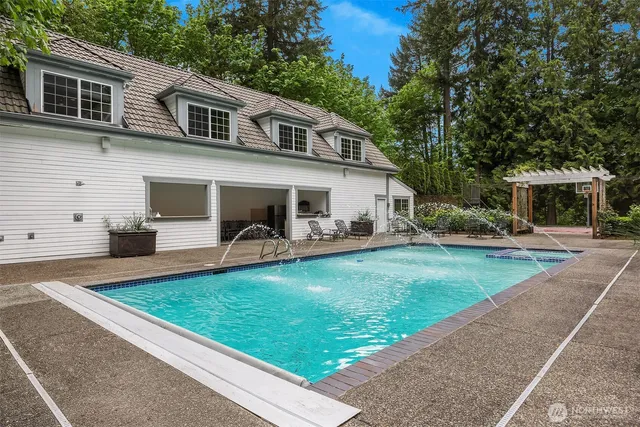 a view of a house with pool lawn chairs and wooden fence
