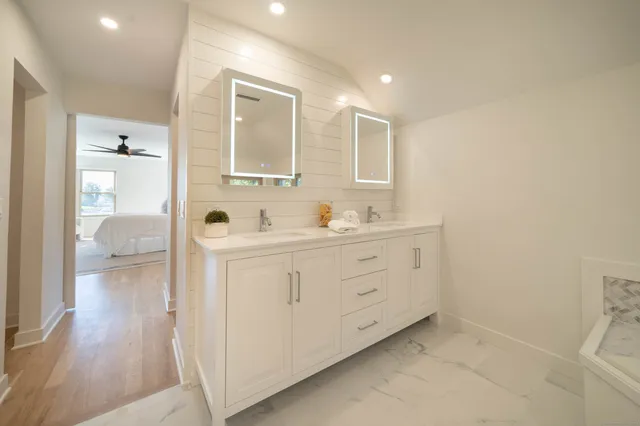 a spacious bathroom with a double vanity sink a mirror and a shower